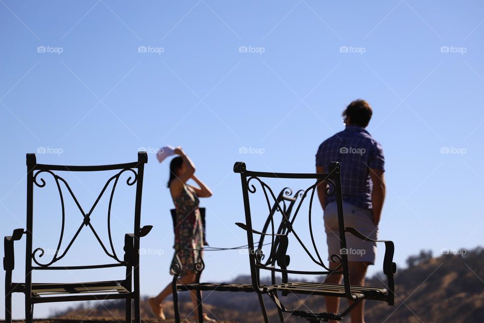 Man watching a woman between two iron chairs 