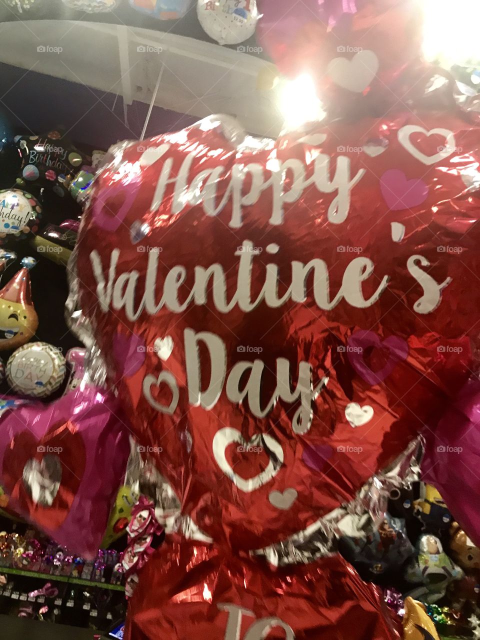 A red, pink and white  heart shaped Happy Valentine’s Day balloon floating in the party store. USA, America 
