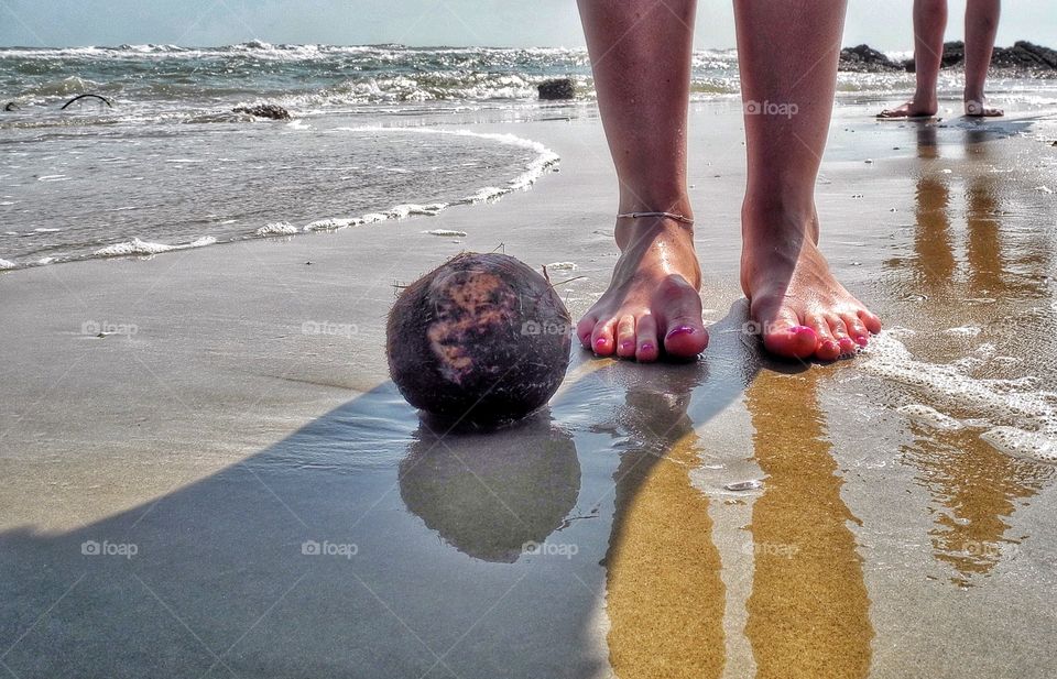 Took this shot on a beach when I went for a walk. My daughter was posing for me when we found that coconut. 