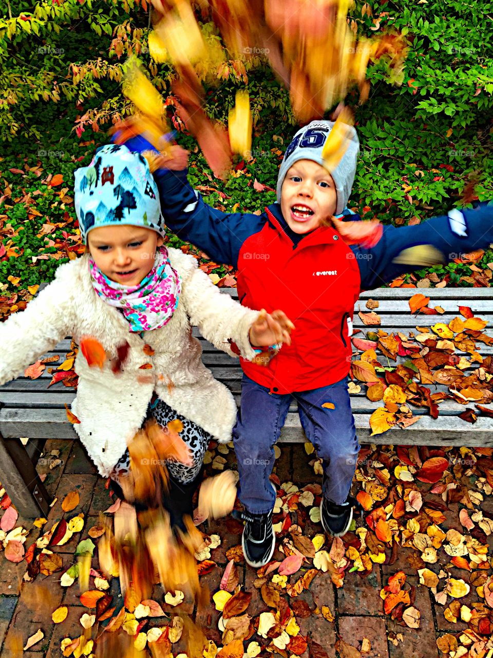 Siblings playing with autumn leaves