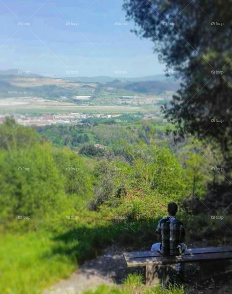 Apreciando el paisaje, sentado en soledad, en un banco del monte