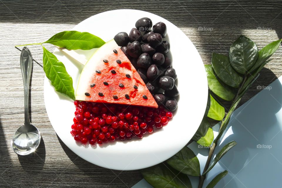 Portion of red watermelon with seeds in the form of a triangle on a wooden table surface