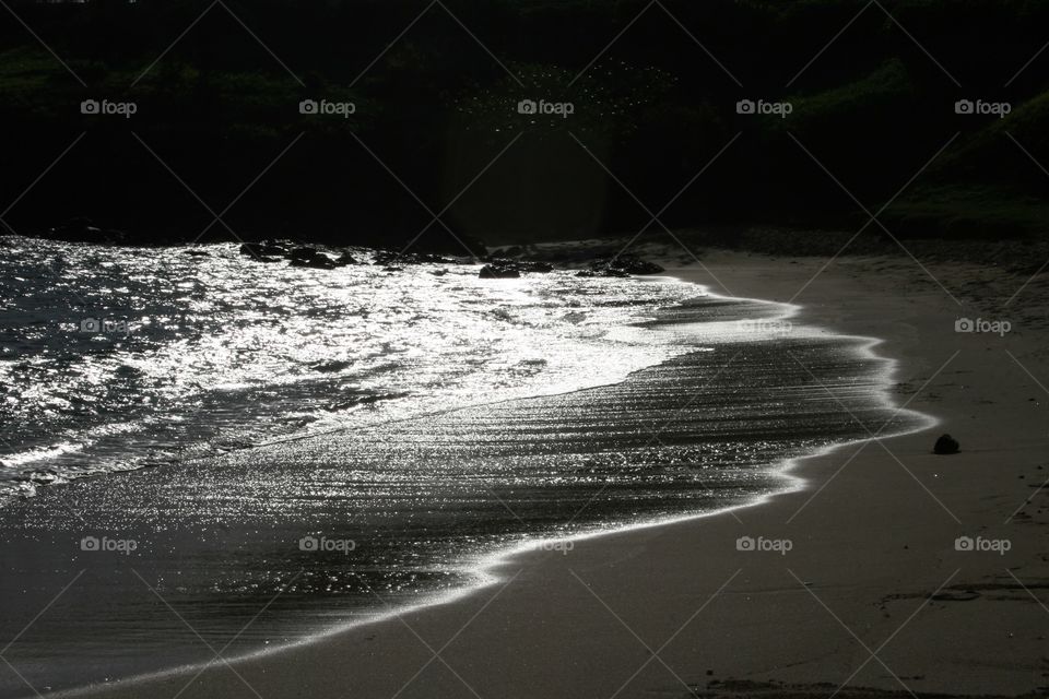 Black Water. Water laps onto the shore of an Hawaiian beach.