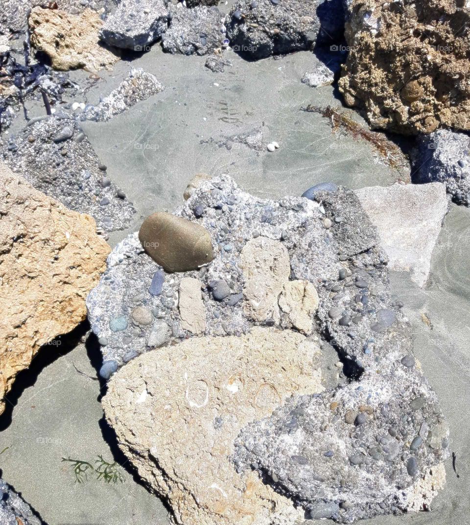The tide is out and leaves some different types of rocks exposed to the sun. The sand is still damp and when the tide comes back in they will again be under water.