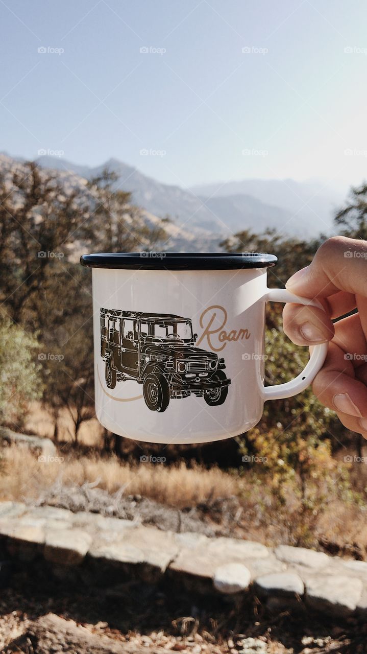 Camping mug being held up to the mountains.