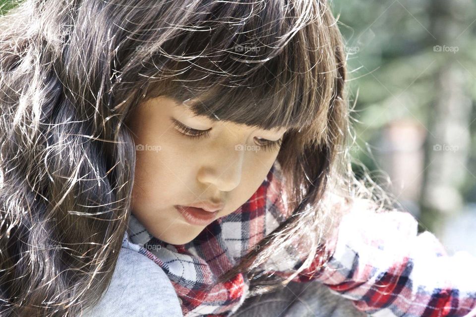 Cute little girl with a beautiful long hair lit by the sun