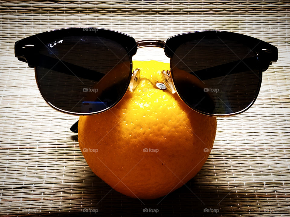 Humor.  Orange in black glasses on a tree mat