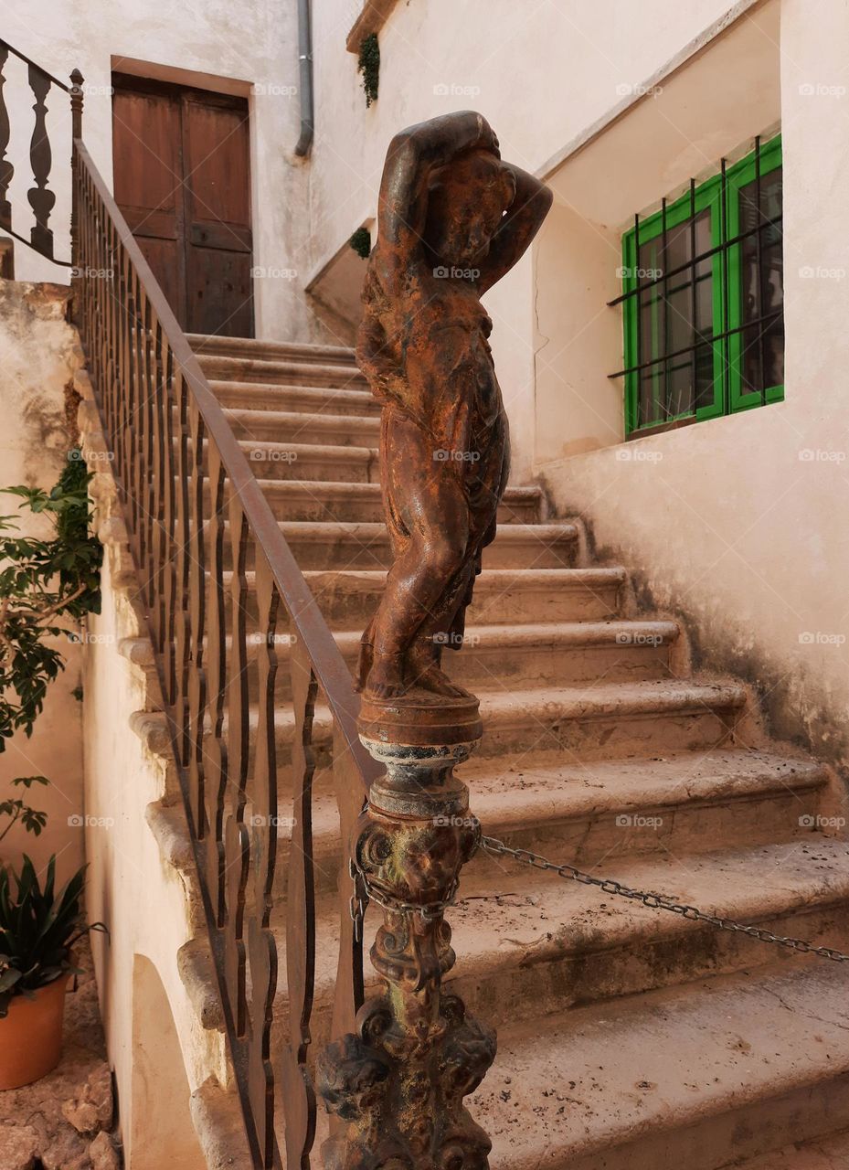 Cast iron figure of a young girl at an ancient staircase. Situated at a courtyard of a Mediterranean traditional manor. Calvia, Majorca, Spain.