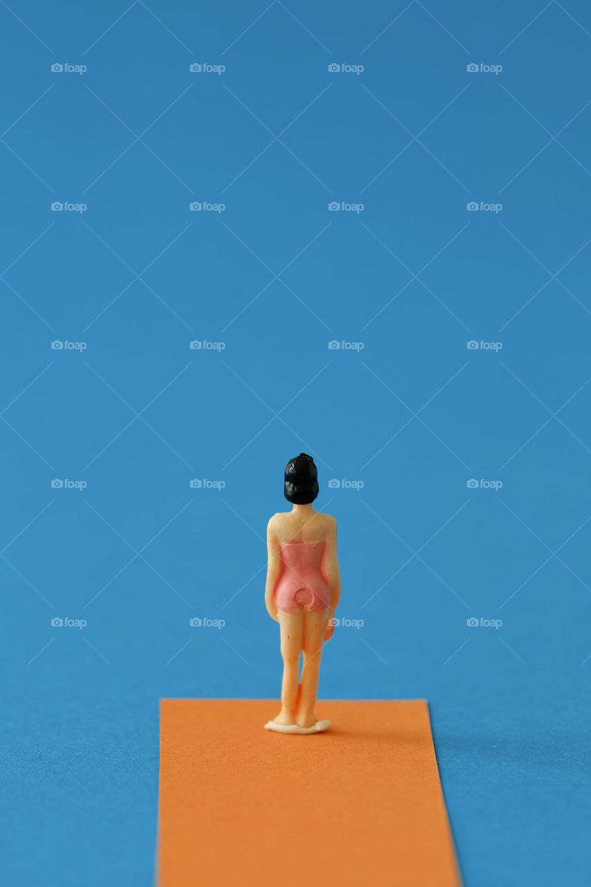 Close-up of miniature figure on orange and blue background.