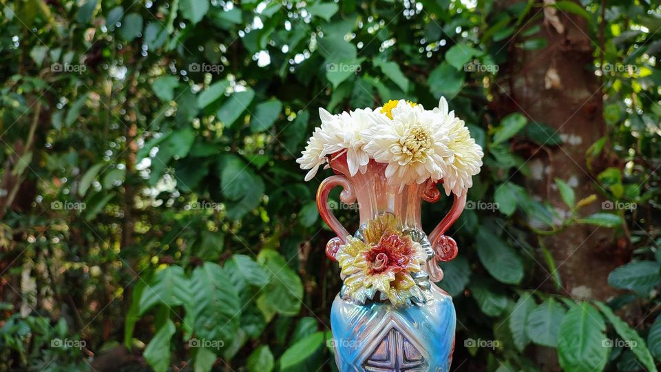 Beautiful white flowers in a colourful flowerpot with a flower sculpture, Flowers in a vase, colourful vase, white flowers in a vase