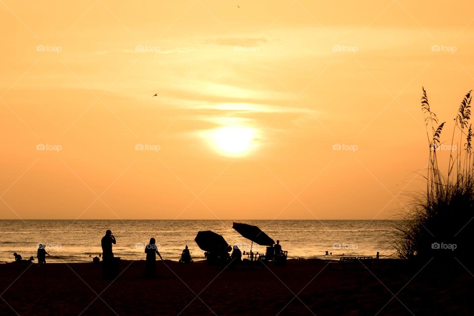 Silhouette of people on the beach by the ocean at beautiful colorful sunset 