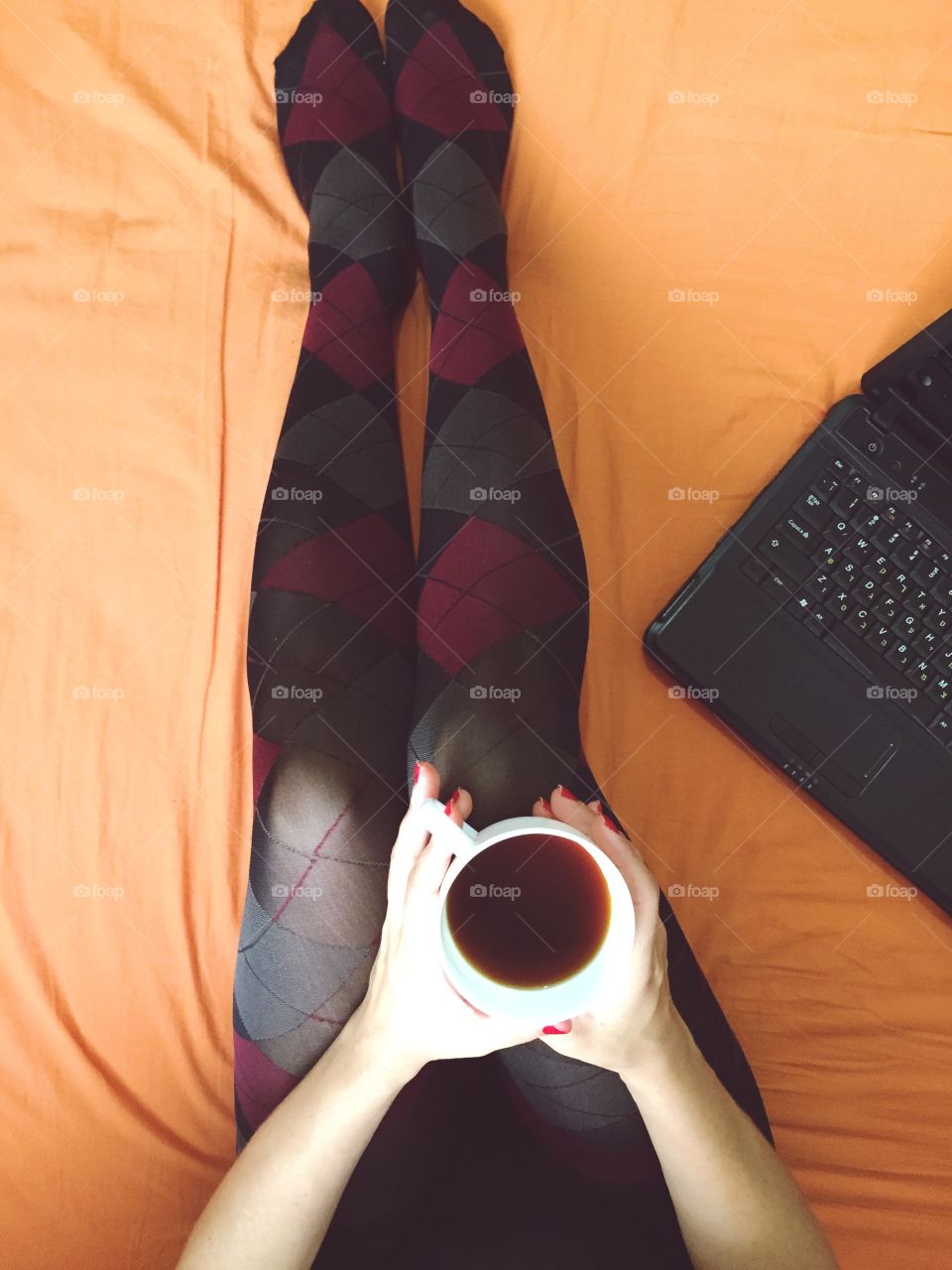 A woman rest on the bed with coffee 