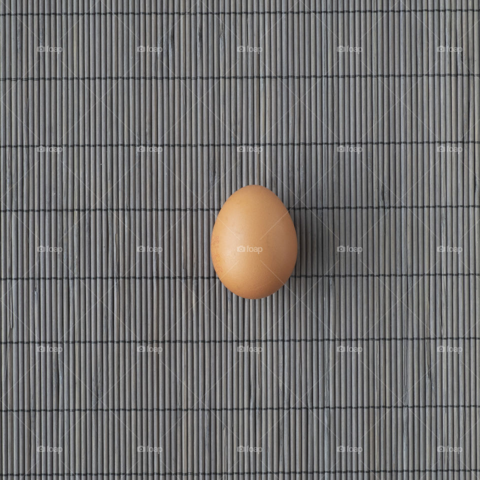 An egg over a grey striped background pattern