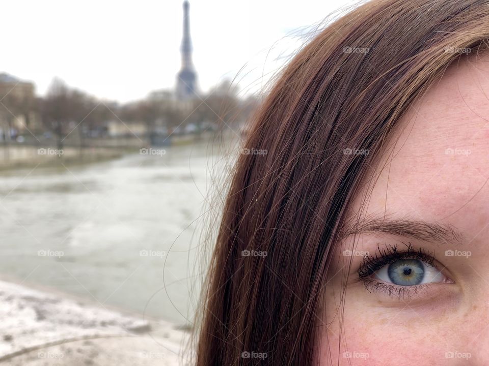 Beautiful blue eyes on a bridge on the Seine River in Paris, France. View of the Eiffel Tower in the background. 