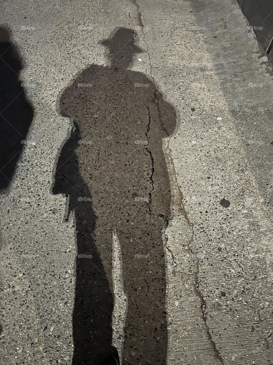 A dramatic shadow emerges when the night illumination of the pedestrian lane of the “Pulaski Bridge” at “Newtown Creek” hits an object. The bridge connects LIC to “Greenpoint”, Bklyn in the direction we are facing. 2023. Hypnotic Productions