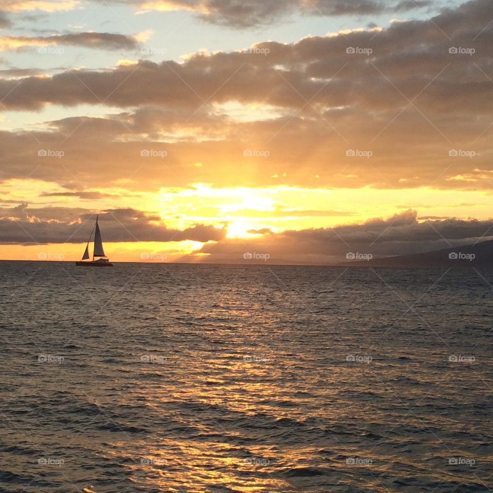 Sunset off the shores of Maui. Staring out at the Hawaiian sunset sail with the ocean's tranquil waters and the sky's blended colors

