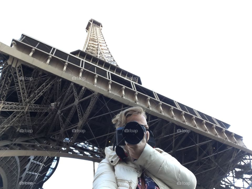 Woman with camera in front of a Eiffel tower