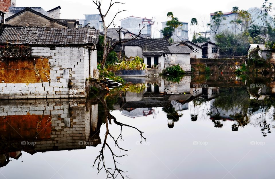 Reflection of some ancient houses over a pond in a village located in Yangshuo, Autonomous Region of Guangxi, China