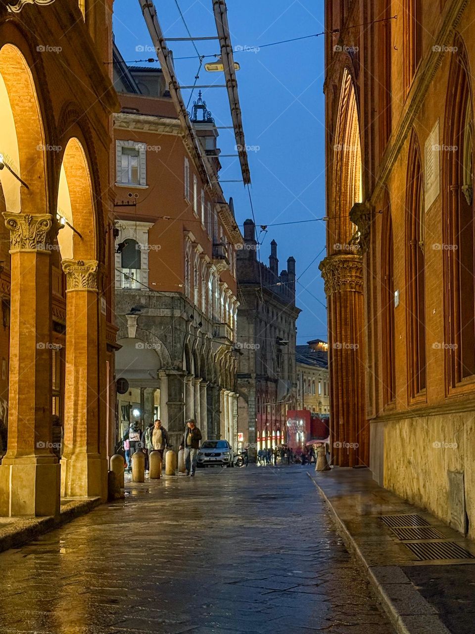 Evening street in Bologna, Italy, after the rain, old architecture, arches, warm light 