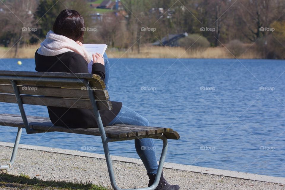 Young Lonely Girl Sitting By Lake Shore