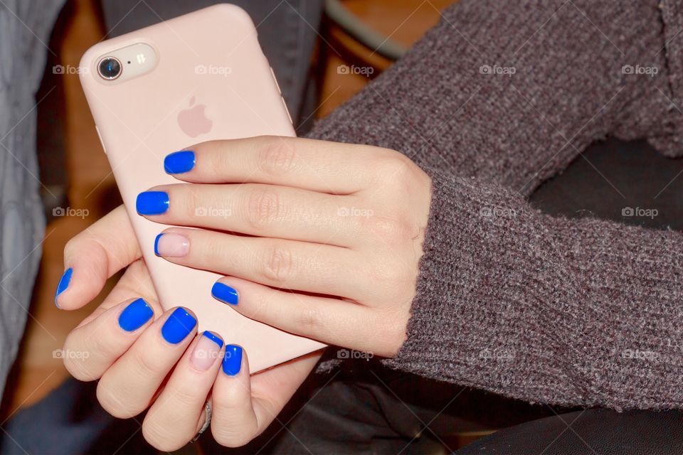 Hands of a girl with nice manicure hold a phone with a pink case