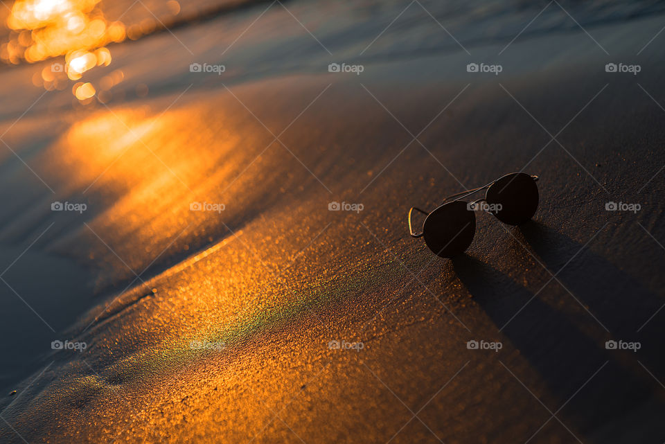 Sunglasses on beach sand during sunset