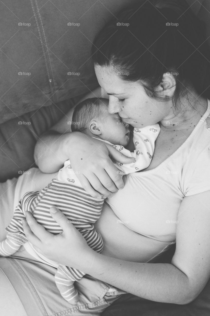 Mother holding her newborn son on chest 