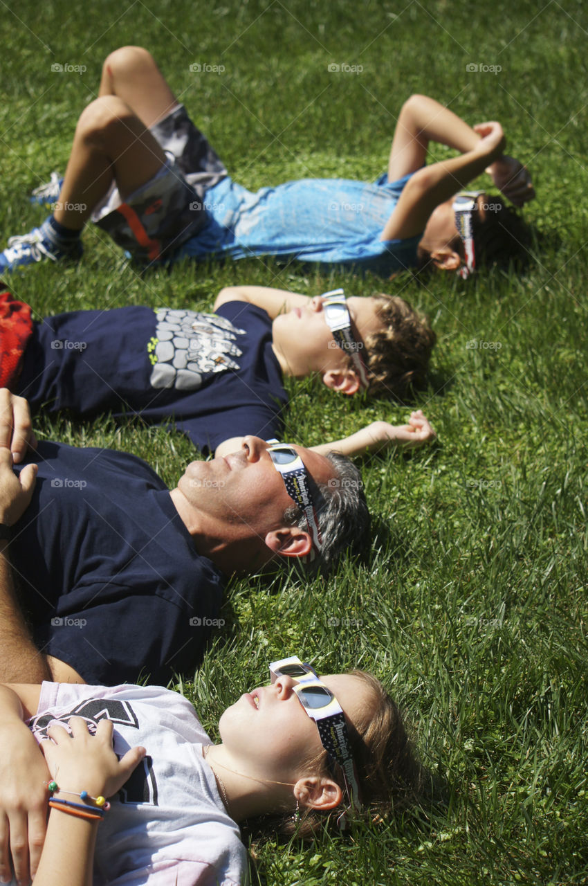 Father and children lying on grass wearing 3d glasses