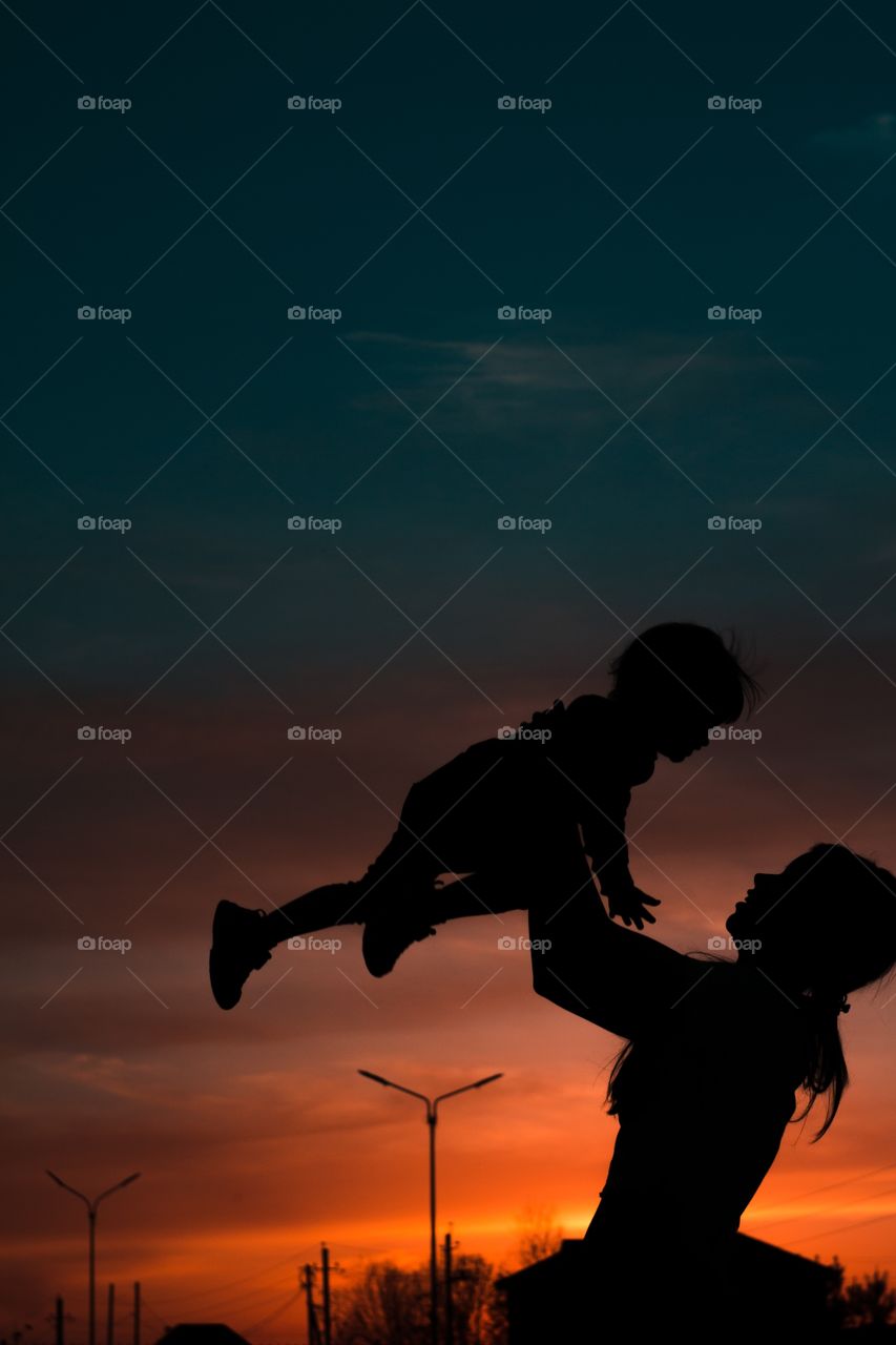 mother and daughter silhouettes against the sky