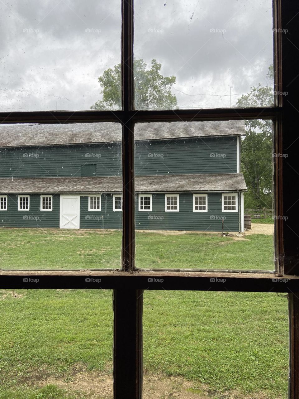 A photo of a green barn taken from the window of the Carriage House at Historic Walnford County Park in Upper Freehold, NJ. It is an area rich in agricultural, technological, environmental and social history dating back over 200 years. 