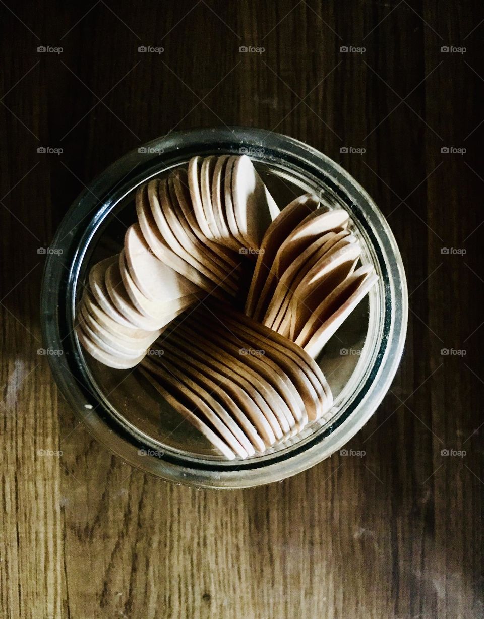 A bundle of Ice-cream sticks in a jar- wood galore. Wooden table