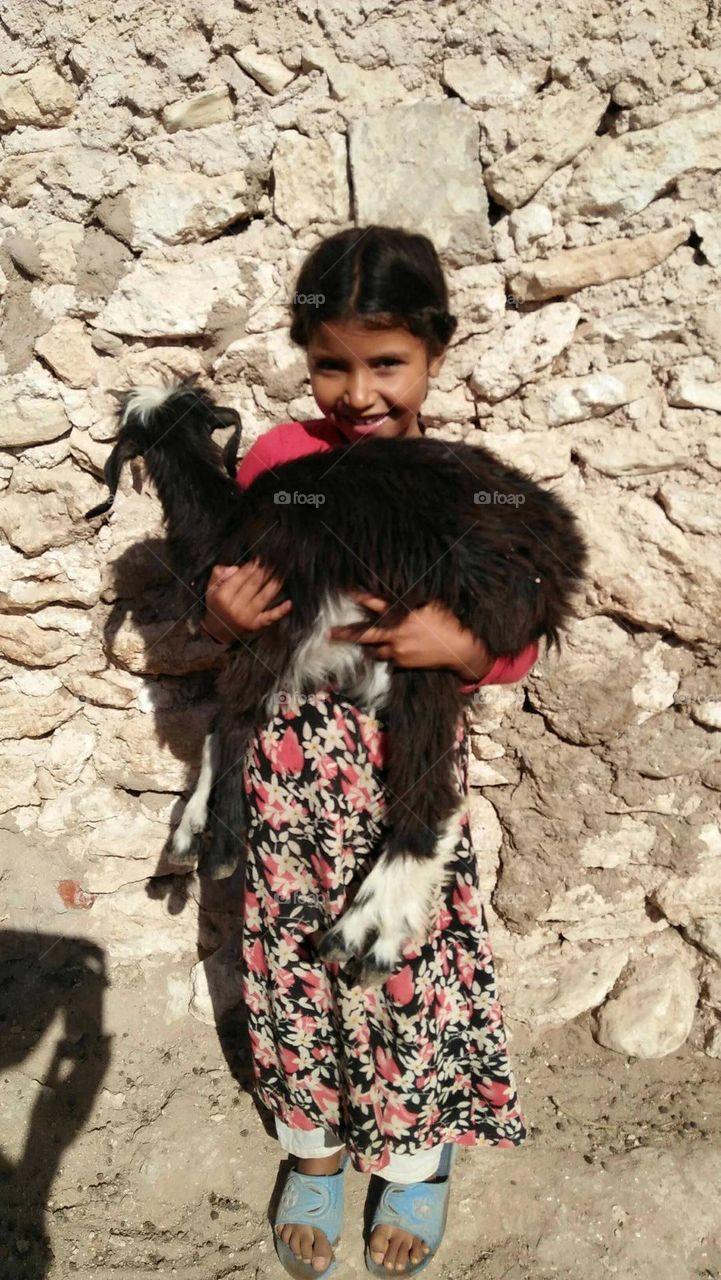 A beautiful girl holding a black goat.