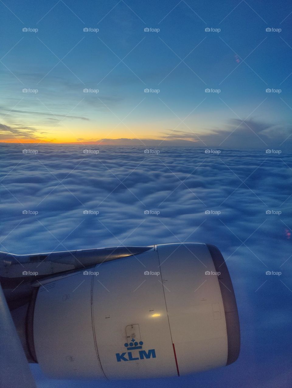 Flying home for Christmas by airplane in the blue cloudy sky with sunset. KLM