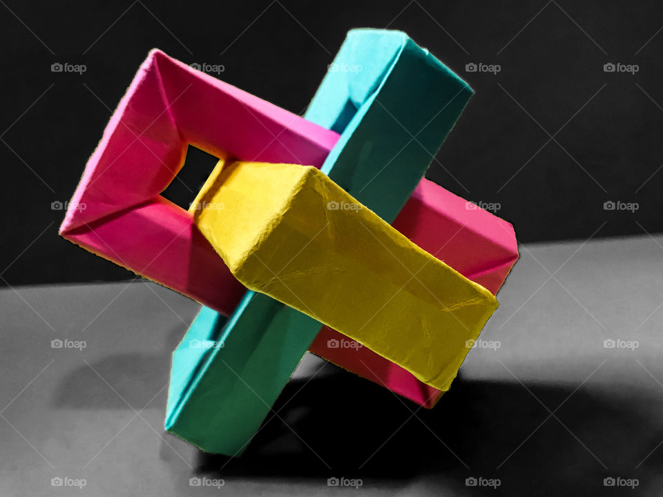 An origami of rectangles called “Umulius rectangulum” or “Magic Rings”. A seemingly impossible interconnecting trio of rectangular boxes on a monochrome grey background. Painstakingly handmade by me!