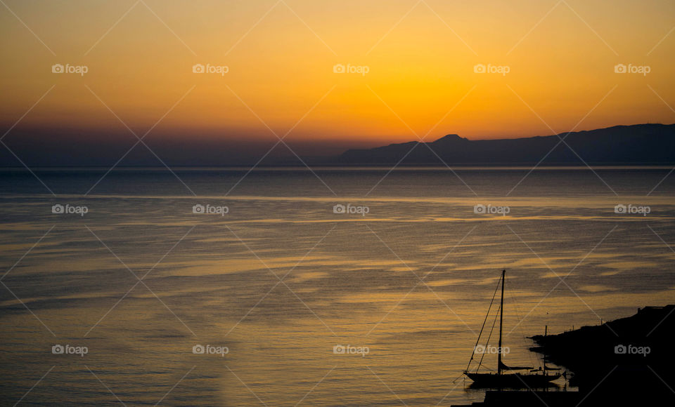 Silhouette of sailboat on beach at sunset