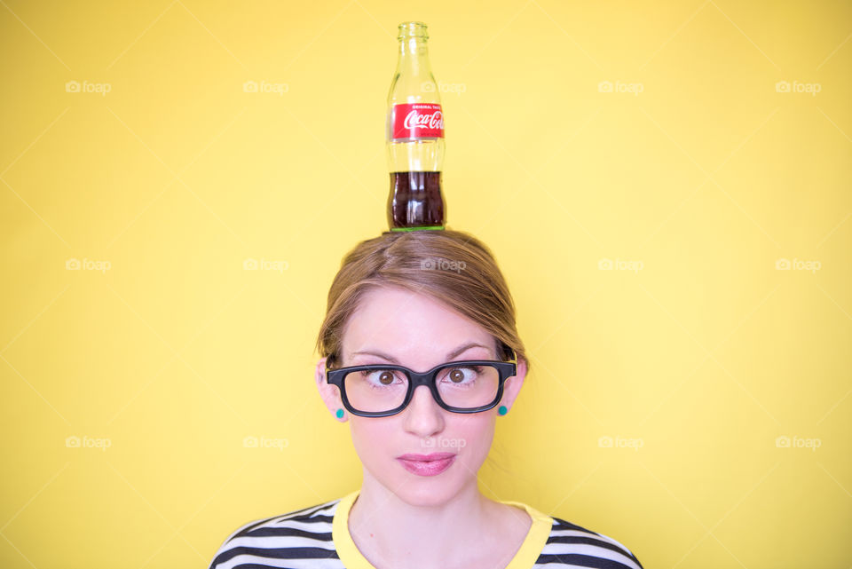 Bright, colorful portrait of a young woman balancing a bottle of Coca-cola on her head