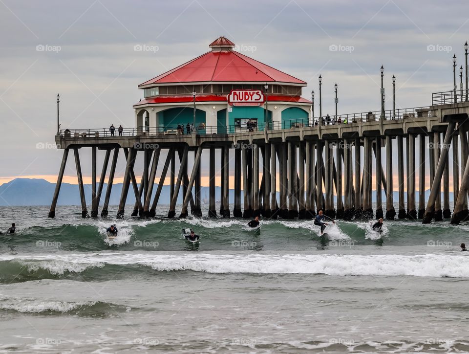Surfers surfing in front of the Huntington Beach Pier