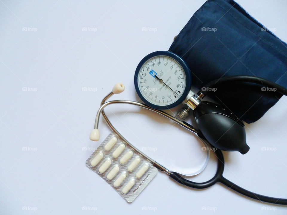 tonometer device for measuring blood pressure and pills on a white background