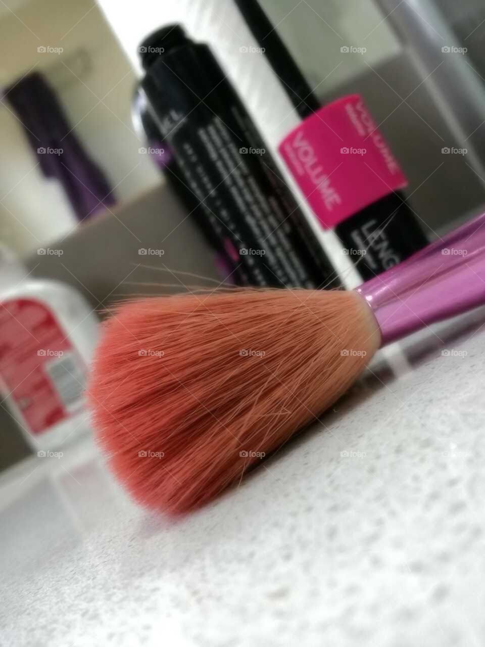 closeup of a makeup blush brush sitting on a bathroom counter top