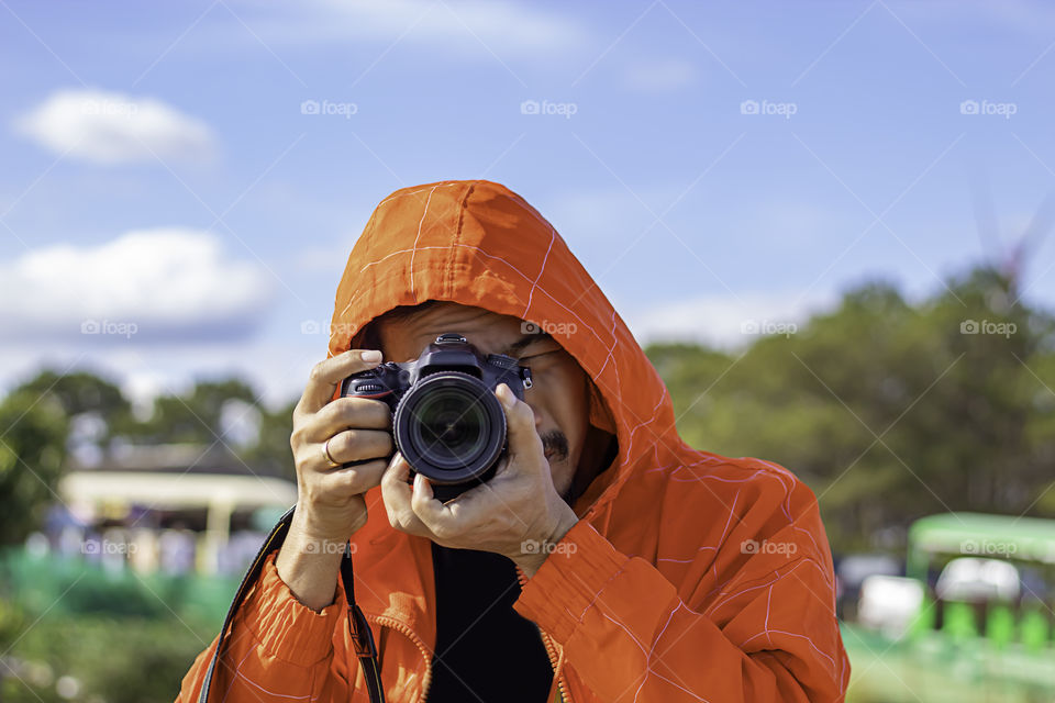 Hand man holding the camera Taking pictures background tree and sky.