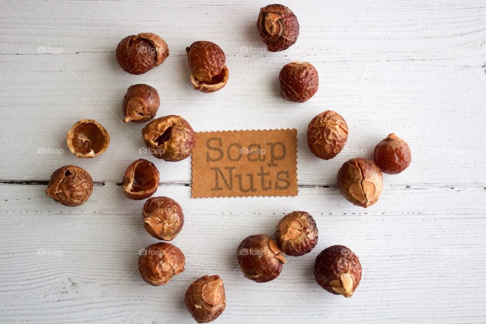 Soap nuts or soap berries on weathered white wooden background with identification placard in natural light