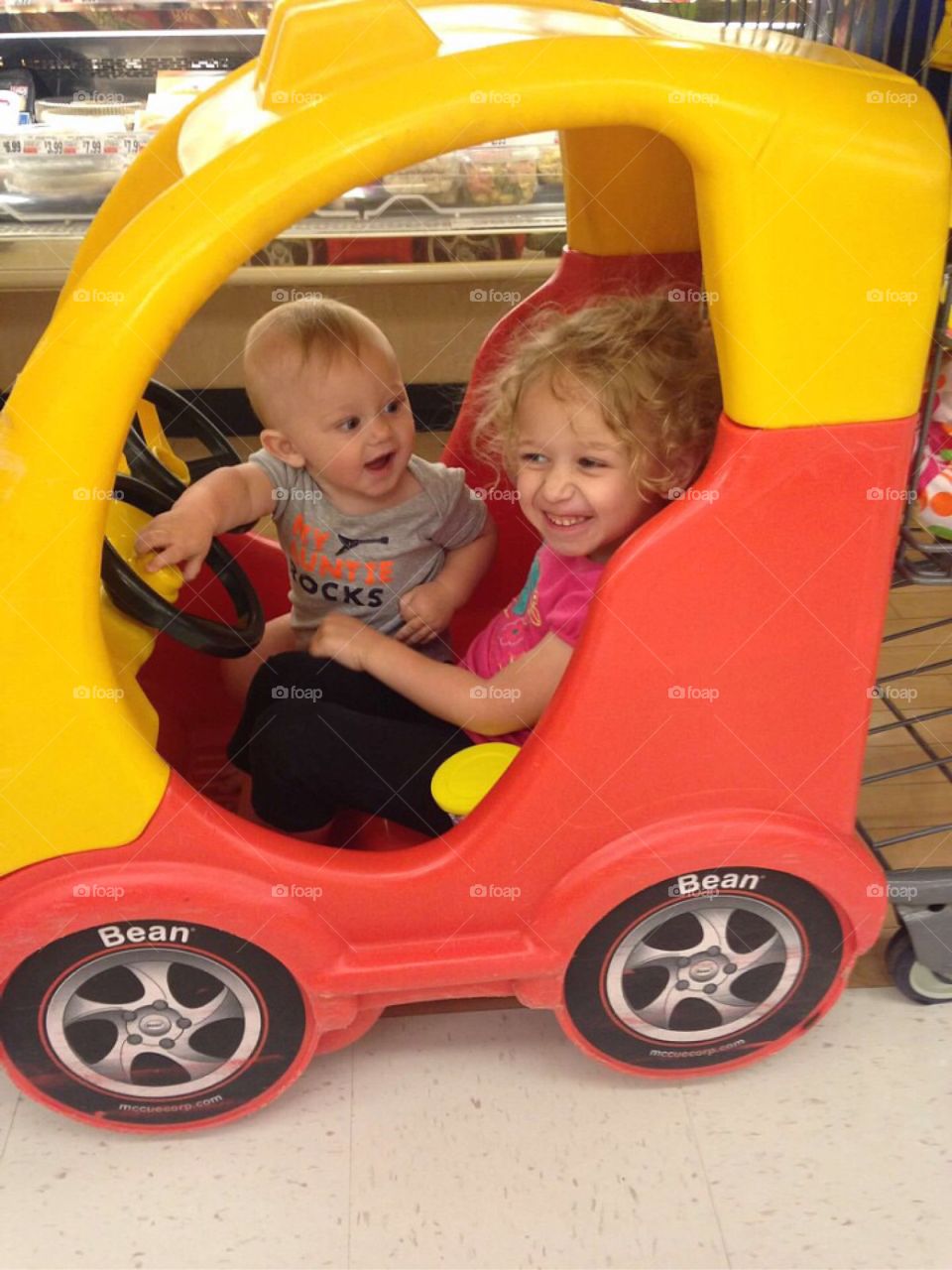 Smiling sibling in toy car