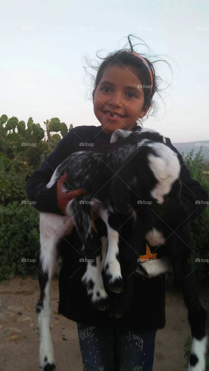 A beautiful girl holding two small black goats