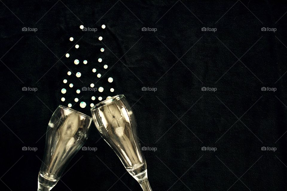 Flat lay of gold-tinted champagne glasses and  rhinestone bubbles on black background