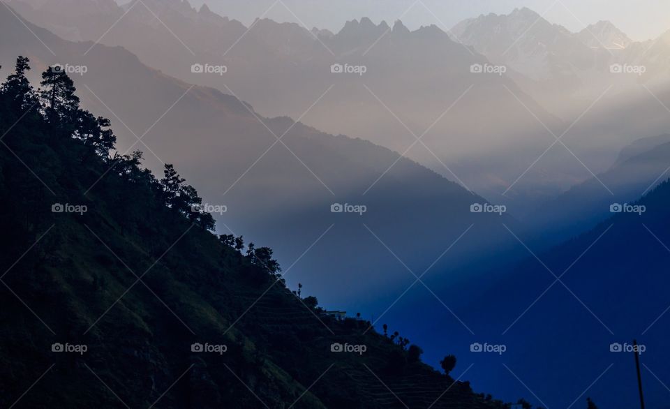 soft winter sunlight breaking thru behind foggy mountains