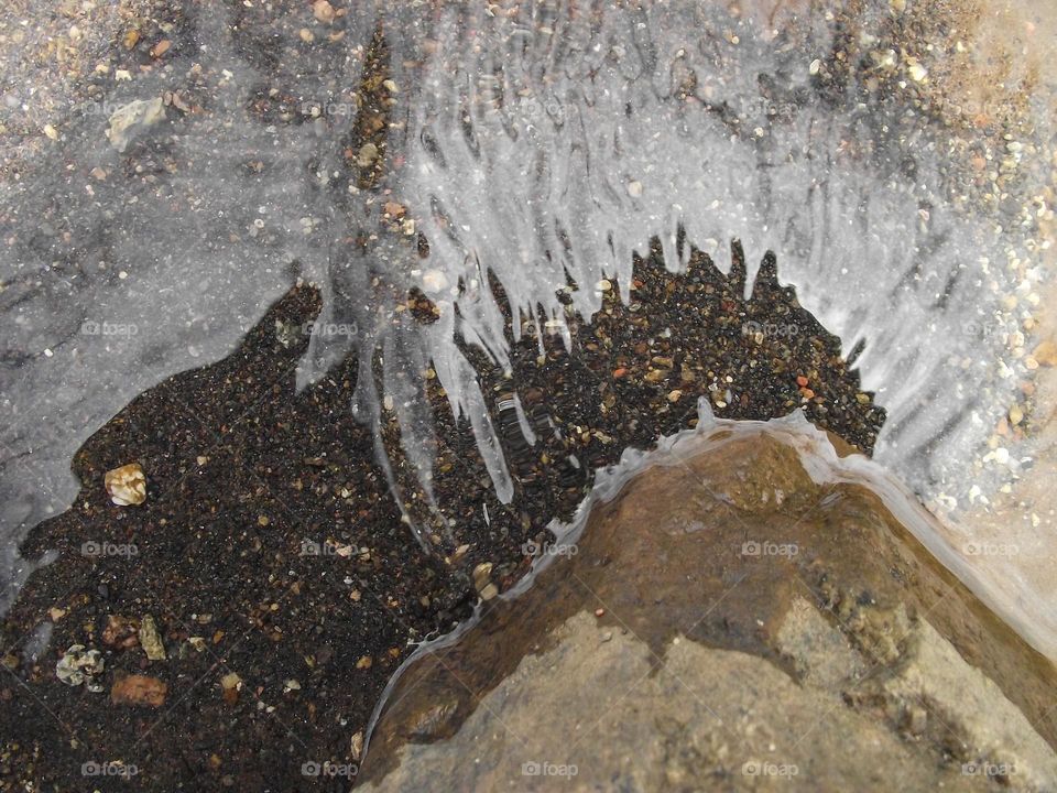 white sky reflecting on the water and the water become clear it bouncing off the rock so u can see the sand