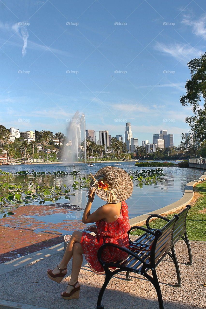 Woman in red dress sitting on bench by the lake