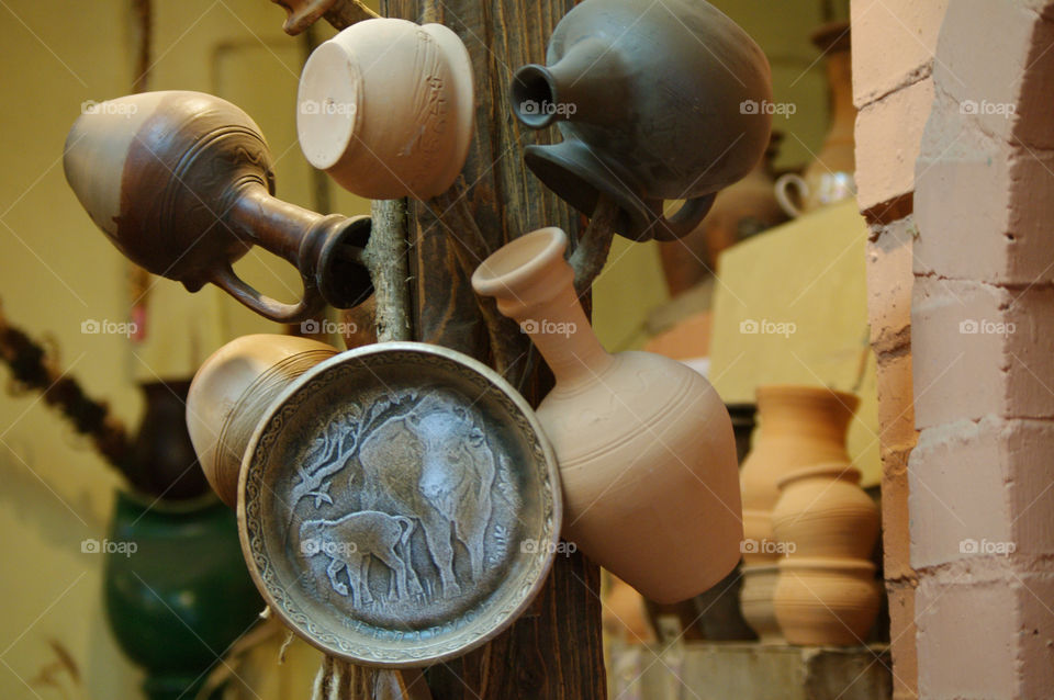 clay pots and vessels stand on a shelf in a rustic kitchen