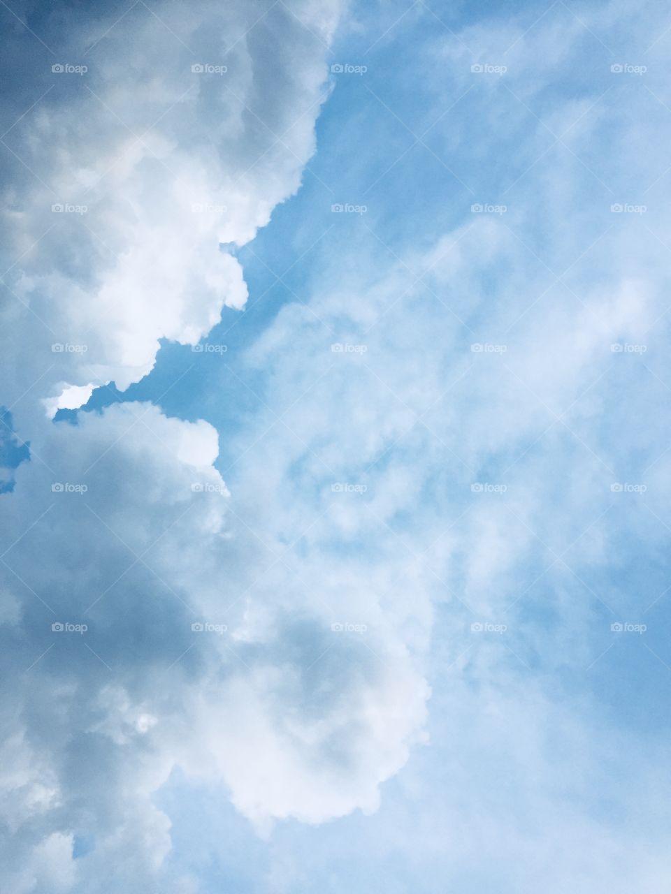 Dark, heavy, rain clouds move in against a bright blue sky with high, thin, wispy clouds 