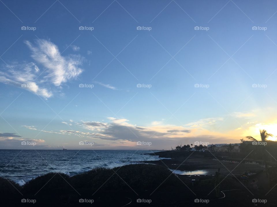 The sun beginning it’s descent below the horizon at the shore front of the town of Costa Teguise, on the island of Lanzarote. 